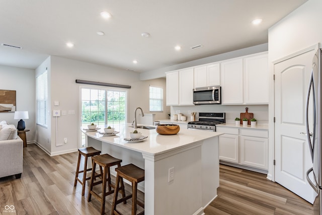 6537 Seabiscuit Rd, Whitestown, IN 46075 - kitchen featuring stainless steel appliances, light wood-style floors, a center island with sink, white cabinetry, and recessed lighting
