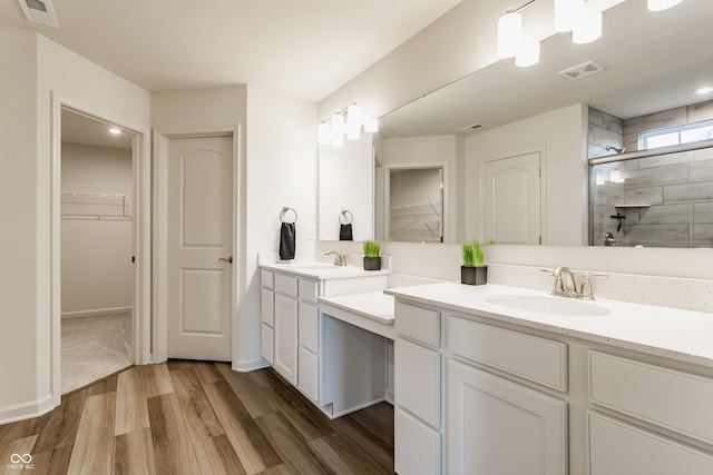 6537 Seabiscuit Rd, Whitestown, IN 46075 - bathroom with double vanity, a walk in closet, a stall shower, and wood finished floors
