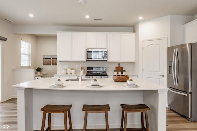 6537 Seabiscuit Rd, Whitestown, IN 46075 - kitchen with appliances with stainless steel finishes, light wood-style floors, white cabinetry, light countertops, and a kitchen bar