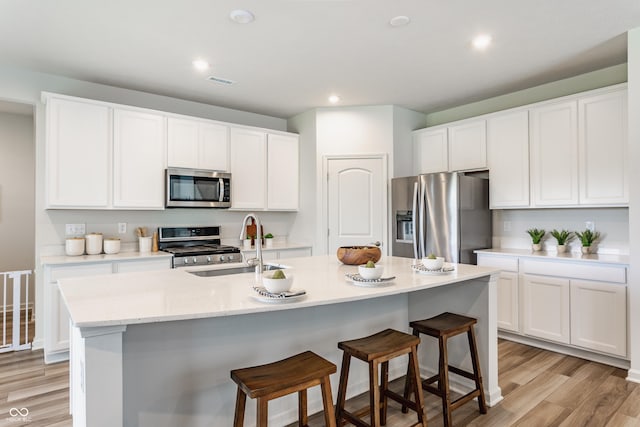 6537 Seabiscuit Rd, Whitestown, IN 46075 - kitchen with appliances with stainless steel finishes, white cabinetry, a breakfast bar area, light wood finished floors, and recessed lighting