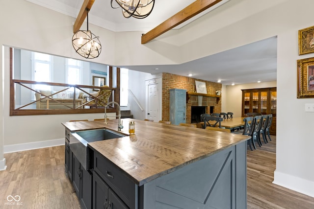 17320 Joliet Rd, Westfield, IN 46074 - kitchen with a chandelier, beam ceiling, a brick fireplace, wood finished floors, and a kitchen island with sink