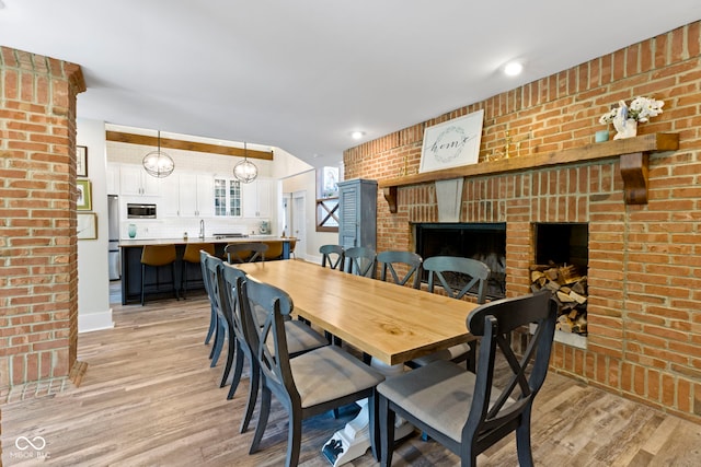 17320 Joliet Rd, Westfield, IN 46074 - dining room featuring light wood-style flooring, brick wall, and a fireplace