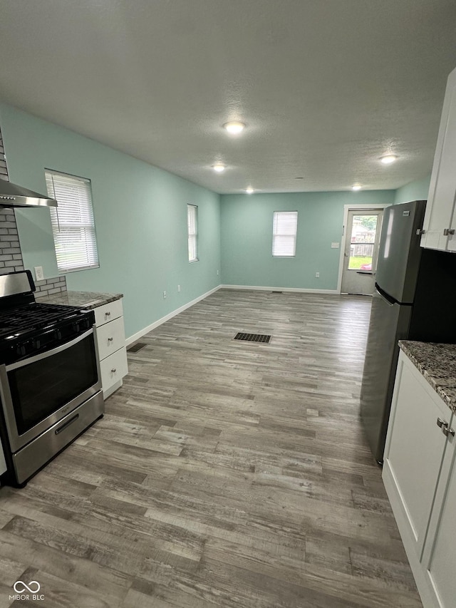 4715 Normal Ave, Indianapolis, IN 46226 - kitchen with stainless steel appliances, white cabinetry, wood finished floors, open floor plan, and light stone counters