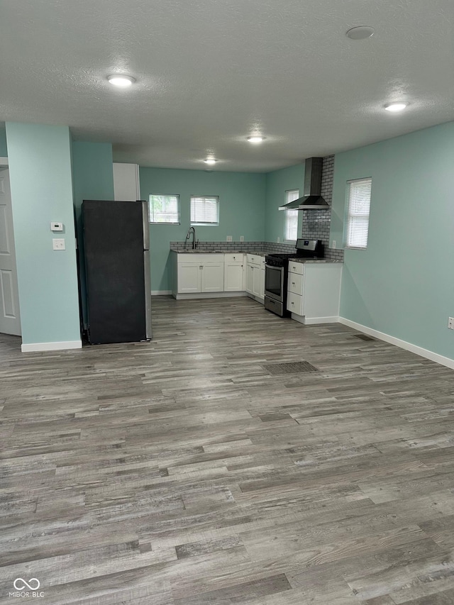 4715 Normal Ave, Indianapolis, IN 46226 - kitchen featuring appliances with stainless steel finishes, wall chimney range hood, wood finished floors, white cabinets, and a textured ceiling