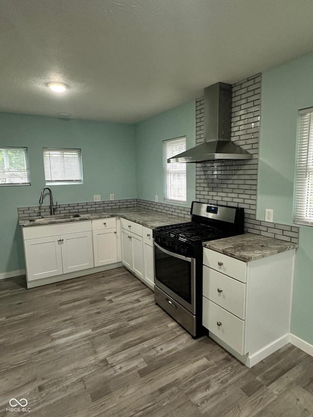 4715 Normal Ave, Indianapolis, IN 46226 - kitchen featuring wall chimney exhaust hood, stainless steel range with gas cooktop, white cabinets, light stone counters, and dark wood finished floors
