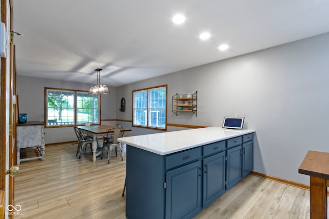 10808 Greenbriar Dr, Fishers, IN 46037 - kitchen featuring blue cabinetry, a peninsula, light wood finished floors, light countertops, and decorative light fixtures