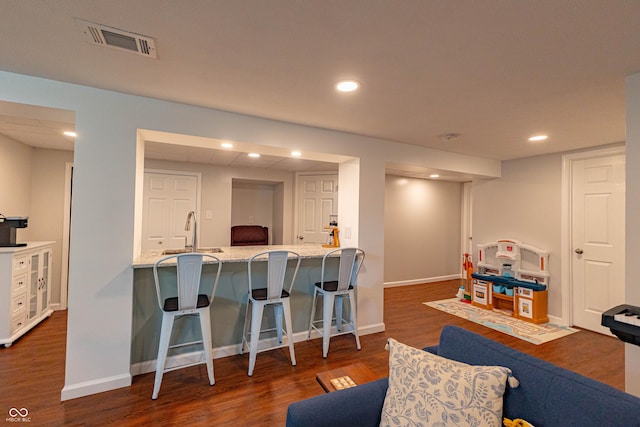 5609 Meadowood Dr, Indianapolis, IN 46224 - kitchen featuring dark wood-type flooring, a kitchen bar, light stone countertops, recessed lighting, and a peninsula