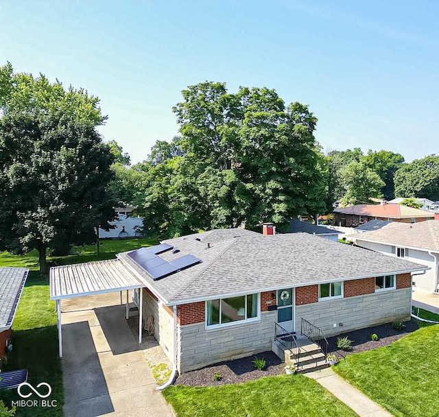 5609 Meadowood Dr, Indianapolis, IN 46224 - view of front of home with stone siding, a shingled roof, a front lawn, and roof mounted solar panels