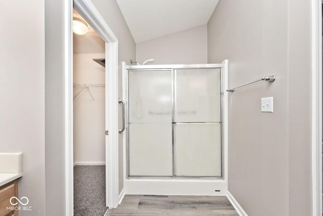 10668 Whippoorwill Ln, Indianapolis, IN 46231 - full bath with a stall shower, vanity, a walk in closet, wood finished floors, and lofted ceiling