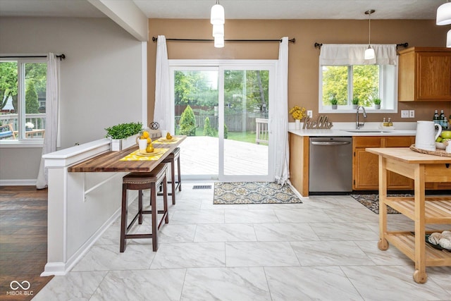 14492 Cotswold Ln, Carmel, IN 46033 - kitchen with stainless steel dishwasher, light countertops, hanging light fixtures, and brown cabinetry