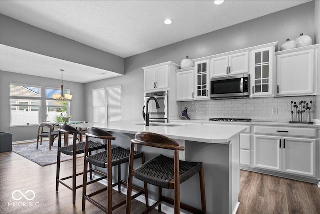 4420 Wild Turkey Dr, Indianapolis, IN 46239 - kitchen featuring appliances with stainless steel finishes, tasteful backsplash, wood finished floors, light countertops, and a breakfast bar area