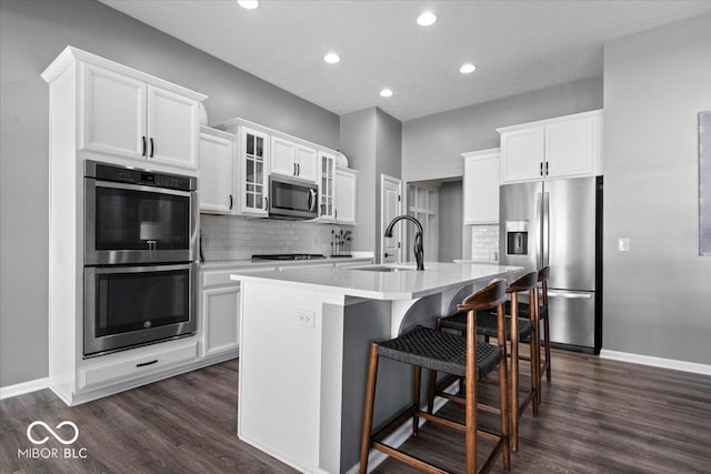 4420 Wild Turkey Dr, Indianapolis, IN 46239 - kitchen with appliances with stainless steel finishes, dark wood-style flooring, an island with sink, backsplash, and recessed lighting