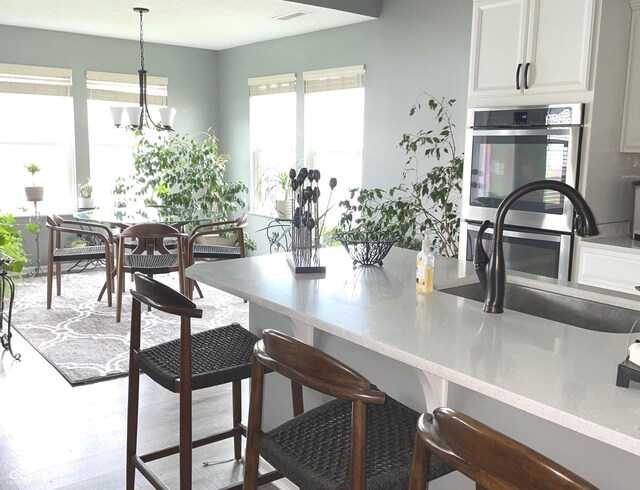 4420 Wild Turkey Dr, Indianapolis, IN 46239 - kitchen featuring a kitchen bar, hanging light fixtures, stainless steel double oven, wood finished floors, and a chandelier