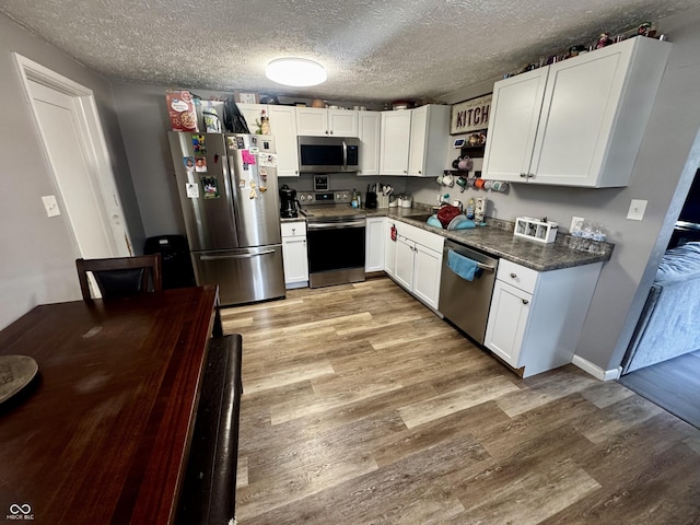 306 Waynetown Rd, Crawfordsville, IN 47933 - kitchen with appliances with stainless steel finishes, light wood finished floors, dark countertops, white cabinetry, and open shelves