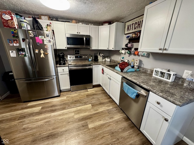306 Waynetown Rd, Crawfordsville, IN 47933 - kitchen featuring appliances with stainless steel finishes, open shelves, a textured ceiling, white cabinetry, and light wood finished floors