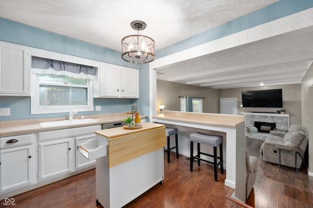 1031 Lancashire Ln, Pendleton, IN 46064 - kitchen featuring a textured ceiling, open floor plan, dark wood finished floors, white cabinetry, and a fireplace