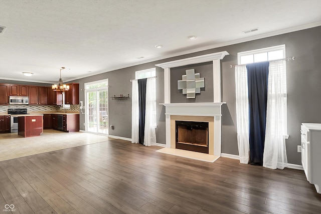 12322 Cool Winds Way W, Fishers, IN 46037 - unfurnished living room with a fireplace with raised hearth, a chandelier, crown molding, and wood finished floors