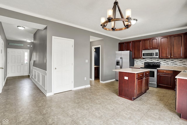 12322 Cool Winds Way W, Fishers, IN 46037 - kitchen featuring appliances with stainless steel finishes, a chandelier, light countertops, a kitchen island, and ornamental molding