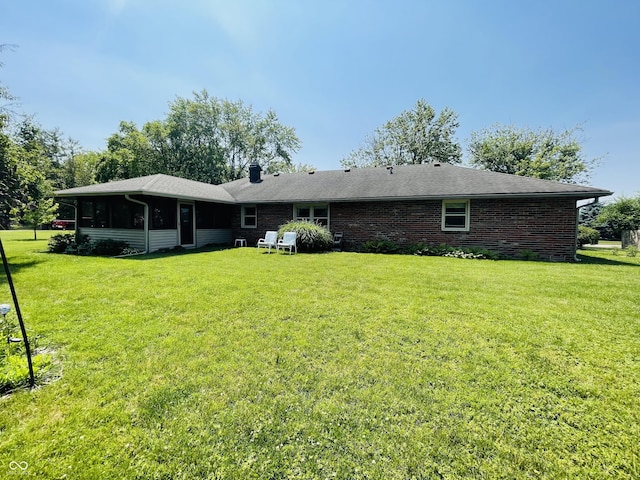 1008 Whispering Trl, Greenfield, IN 46140 - rear view of house featuring a yard, a chimney, a sunroom, and brick siding