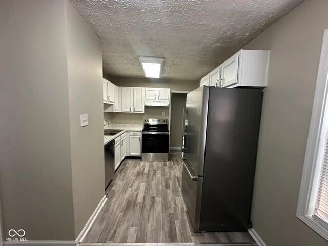 5704 N Keystone Ave, Indianapolis, IN 46220 - kitchen featuring stainless steel appliances, a textured ceiling, wood finished floors, white cabinetry, and under cabinet range hood