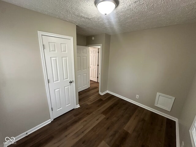 5704 N Keystone Ave, Indianapolis, IN 46220 - unfurnished bedroom featuring dark wood-style flooring and a textured ceiling