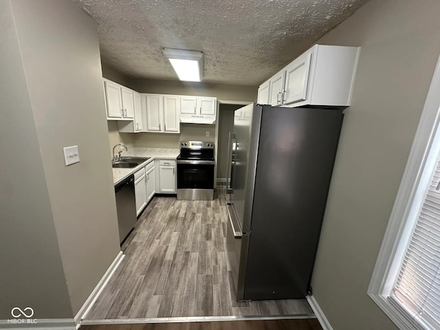 5704 N Keystone Ave, Indianapolis, IN 46220 - kitchen with appliances with stainless steel finishes, a textured ceiling, wood finished floors, white cabinetry, and under cabinet range hood