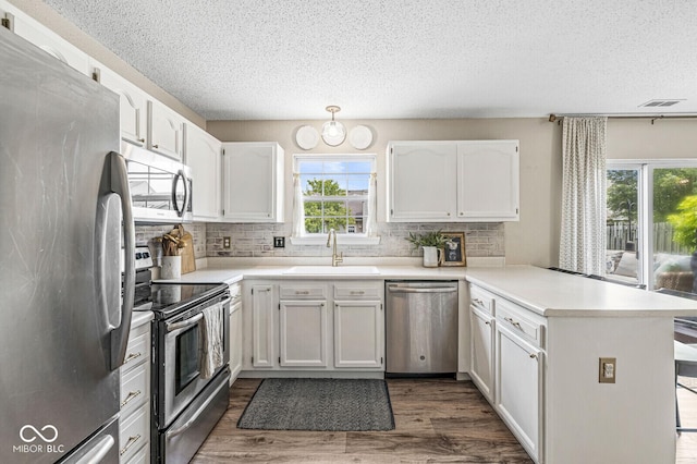 12259 Sweet Creek Trl, Fishers, IN 46037 - kitchen featuring stainless steel appliances, a peninsula, a textured ceiling, decorative backsplash, and white cabinetry