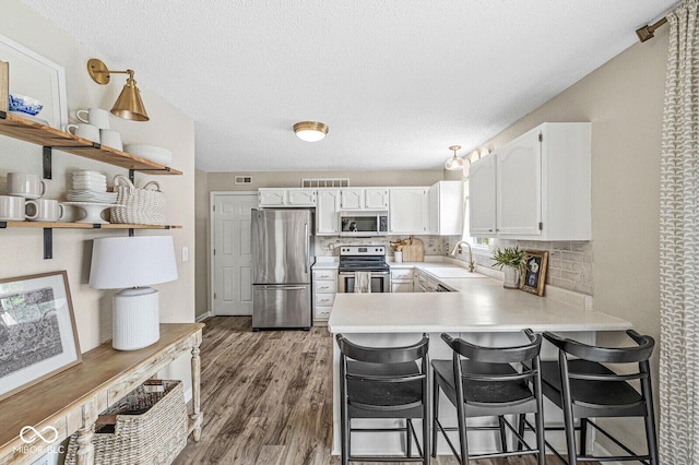 12259 Sweet Creek Trl, Fishers, IN 46037 - kitchen with appliances with stainless steel finishes, a peninsula, open shelves, white cabinets, and light countertops