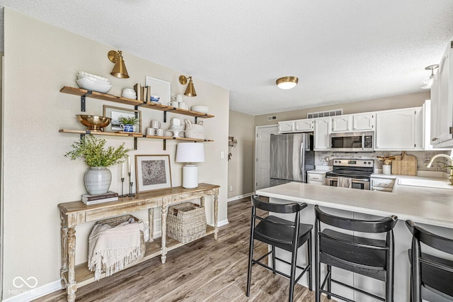12259 Sweet Creek Trl, Fishers, IN 46037 - kitchen with stainless steel appliances, white cabinets, a peninsula, light countertops, and light wood-type flooring