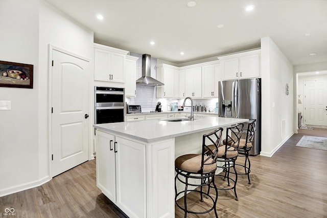 2612 Ruffian Dr, Westfield, IN 46074 - kitchen with wall chimney exhaust hood, appliances with stainless steel finishes, light wood finished floors, decorative backsplash, and a kitchen breakfast bar