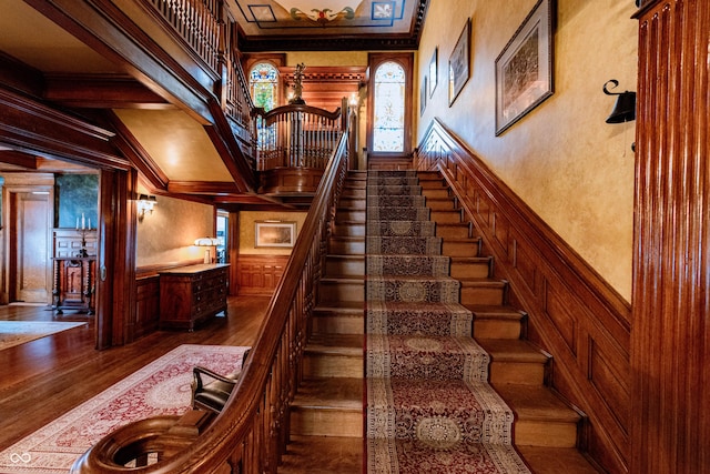 825 E Washington St, Muncie, IN 47305 - staircase with wood finished floors, crown molding, a decorative wall, a wainscoted wall, and a towering ceiling