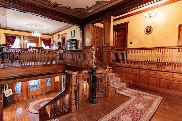 825 E Washington St, Muncie, IN 47305 - staircase with a chandelier, ornamental molding, wood finished floors, a wainscoted wall, and a decorative wall