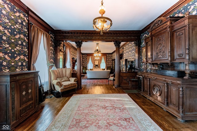 825 E Washington St, Muncie, IN 47305 - hallway featuring ornate columns, dark wood finished floors, crown molding, wallpapered walls, and a chandelier
