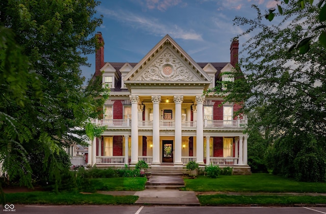 825 E Washington St, Muncie, IN 47305 - greek revival house featuring a balcony, a porch, a chimney, and a front yard
