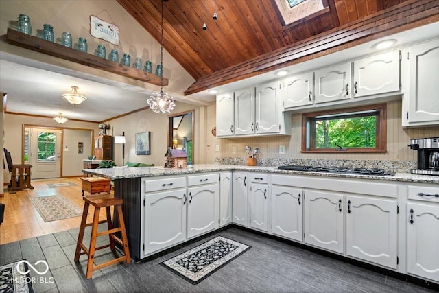 6975 Milhouse Rd, Indianapolis, IN 46221 - kitchen with a peninsula, gas cooktop, vaulted ceiling, tasteful backsplash, and white cabinetry