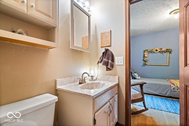 6975 Milhouse Rd, Indianapolis, IN 46221 - bathroom with vanity, a textured ceiling, ensuite bathroom, and wood finished floors