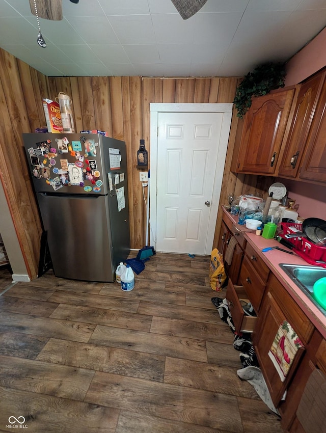 1609 Brown St, Anderson, IN 46016 - kitchen featuring freestanding refrigerator, brown cabinetry, dark wood-style flooring, wooden walls, and light countertops