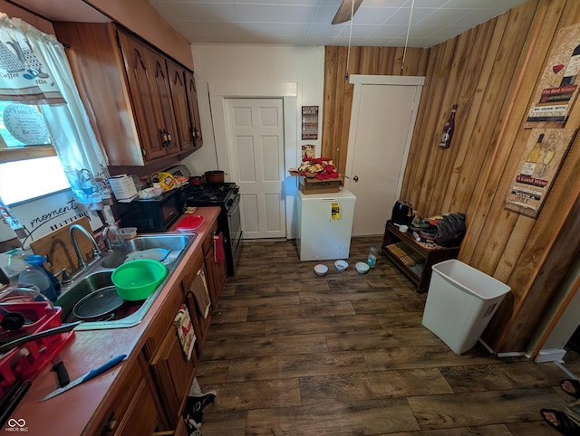 1609 Brown St, Anderson, IN 46016 - kitchen with dark wood-style floors, wood walls, range with gas cooktop, fridge, and washer / clothes dryer