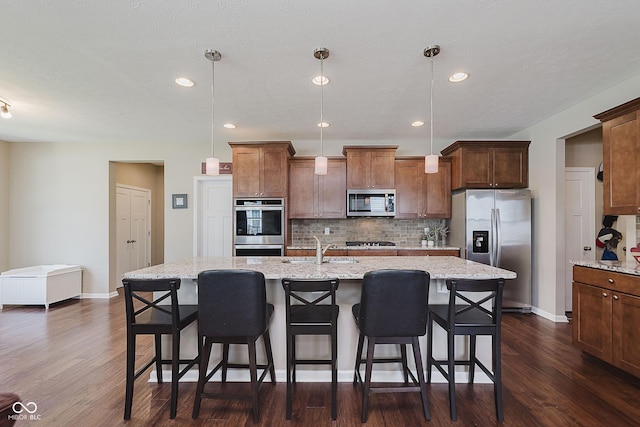 11840 Crossbill Ct, Noblesville, IN 46060 - kitchen with appliances with stainless steel finishes, tasteful backsplash, dark wood-style flooring, an island with sink, and recessed lighting