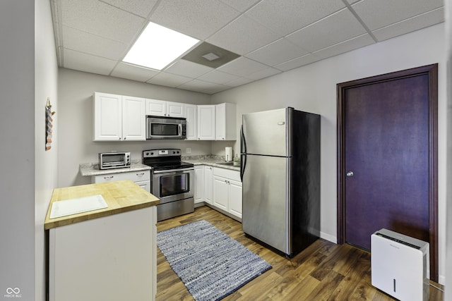 5823 E Sheridan Rd, Monticello, IN 47960 - kitchen featuring appliances with stainless steel finishes, wooden counters, a drop ceiling, white cabinets, and dark wood-style flooring