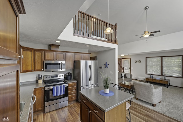 5823 E Sheridan Rd, Monticello, IN 47960 - kitchen with appliances with stainless steel finishes, open floor plan, wood finished floors, a ceiling fan, and a breakfast bar area