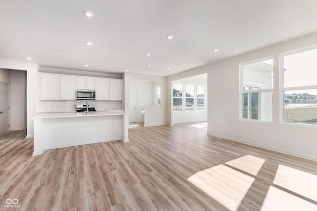 18955 Seaforth Way, Westfield, IN 46074 - kitchen featuring stainless steel microwave, open floor plan, light countertops, stove, and backsplash