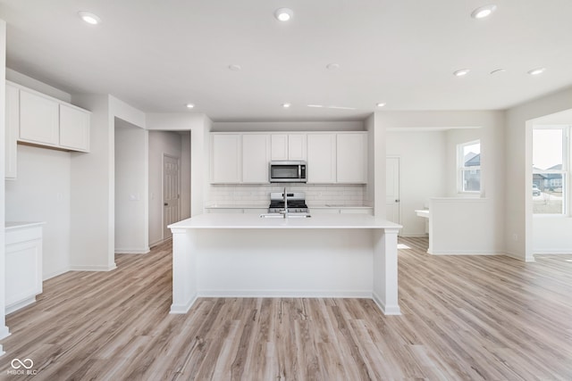 18955 Seaforth Way, Westfield, IN 46074 - kitchen featuring stainless steel appliances, decorative backsplash, light countertops, light wood-style flooring, and a kitchen island with sink