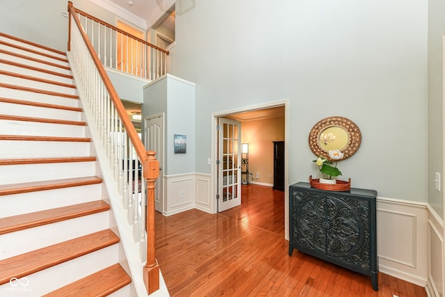 14109 Secretariat Ct, Carmel, IN 46074 - staircase featuring a towering ceiling, wood-type flooring, a wainscoted wall, a decorative wall, and french doors