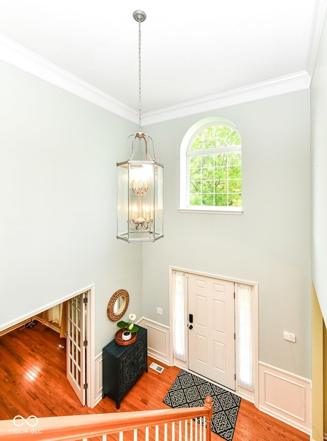 14109 Secretariat Ct, Carmel, IN 46074 - foyer entrance featuring crown molding, wood finished floors, a chandelier, a wainscoted wall, and a towering ceiling