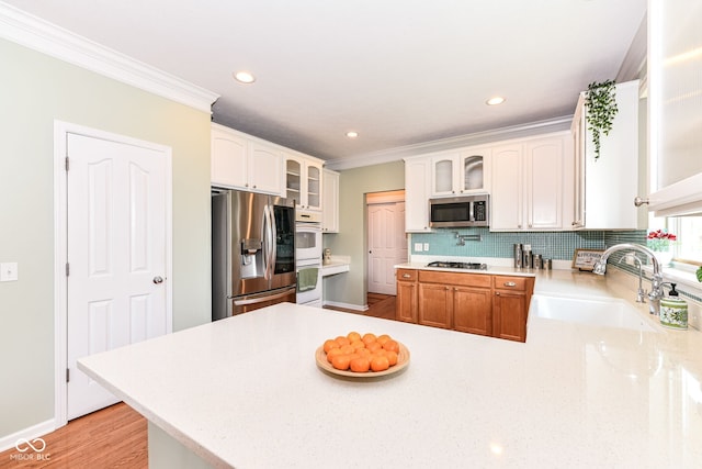 14109 Secretariat Ct, Carmel, IN 46074 - kitchen with stainless steel appliances, a peninsula, glass insert cabinets, backsplash, and ornamental molding