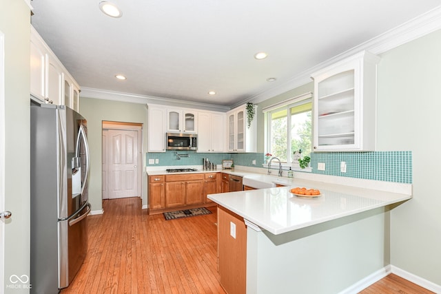 14109 Secretariat Ct, Carmel, IN 46074 - kitchen with appliances with stainless steel finishes, a peninsula, backsplash, light countertops, and ornamental molding