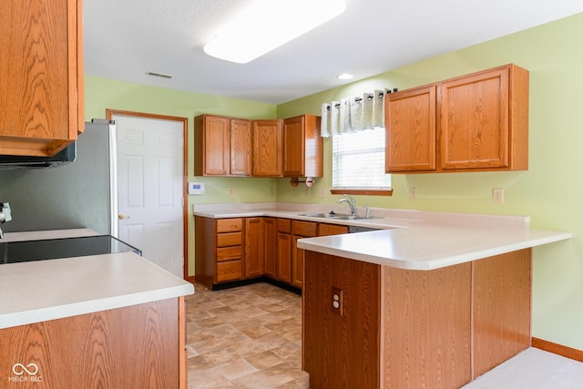 413 Blue Spring Dr, Indianapolis, IN 46239 - kitchen featuring a peninsula, light countertops, freestanding refrigerator, stove, and brown cabinetry