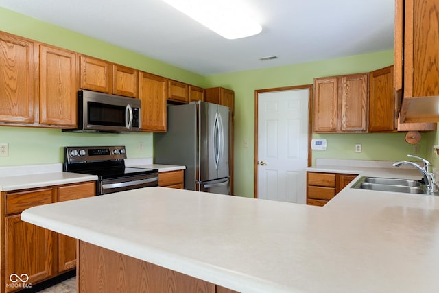 413 Blue Spring Dr, Indianapolis, IN 46239 - kitchen featuring appliances with stainless steel finishes, light countertops, brown cabinets, and a peninsula