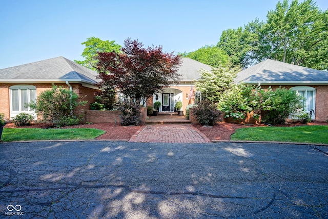 9420 N Kenwood Ave, Indianapolis, IN 46260 - obstructed view of property featuring brick siding, a porch, and roof with shingles